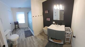 A bathroom with a white sink, dark cabinets, a mirror, and a shower area.