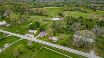An aerial view of a rural property with a main house, a pond, and surrounding greenery.