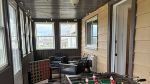 Una stanza con tavolo da calcio, tavolo da biliardo e un angolo relax con sedie.