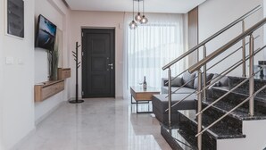 A modern living room with a staircase, a flat-screen TV, a coffee table, and a sofa.