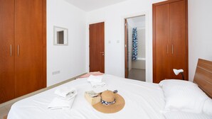 Ein Schlafzimmer mit Bett, Holzschrank, Spiegel und einer Badezimmertür.