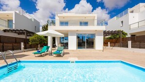 Ein modernes, zweistöckiges Gebäude mit Swimmingpool, Außenbereich und blauem Himmel.