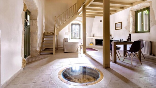 A spacious room with a central circular skylight, a staircase, and a dining area with chairs and a table. - Villa Nafsika in Vamos (Apokoronas)