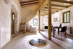 A spacious room with a central circular skylight, a staircase, and a dining area with chairs and a table. - Villa Nafsika in Vamos (Apokoronas)