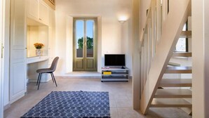 A hallway with a staircase, a television, a chair, and a door leading outside. - Villa Nafsika in Vamos (Apokoronas)