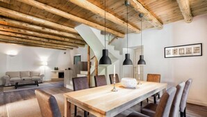 A dining area with a wooden table and chairs, a staircase, and a sofa in the background. - Villa Nafsika in Vamos (Apokoronas)