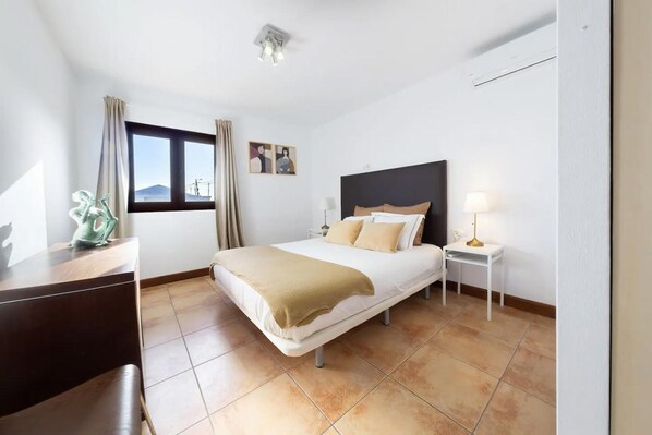 A hotel room with a bed, bedside tables, a desk, and a window with curtains. - Villa Asomada in La Asomada (Tías)