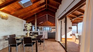 A spacious dining area with a high ceiling and wooden beams, a kitchen with modern appliances, and a view of the city through large windows. - Villa Asomada in La Asomada (Tías)