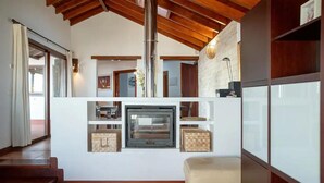 A modern living room with a fireplace, wooden beams, and a view of the outdoors. - Villa Asomada in La Asomada (Tías)
