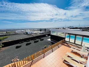 Eine Dachterrasse mit Schwimmbad, Liegestühlen und Blick auf die Stadt.