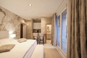 Relax in a spacious room with a large bed, desk area, and kitchenette.