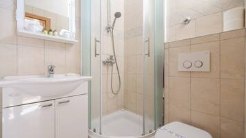 Un baño con ducha de vidrio, lavabo e inodoro.