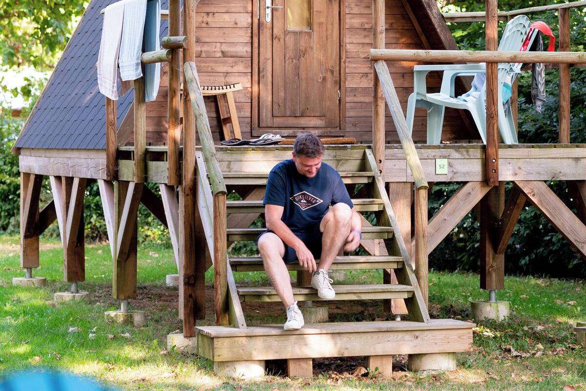 Une cabane en bois avec une véranda, un escalier et une petite table.