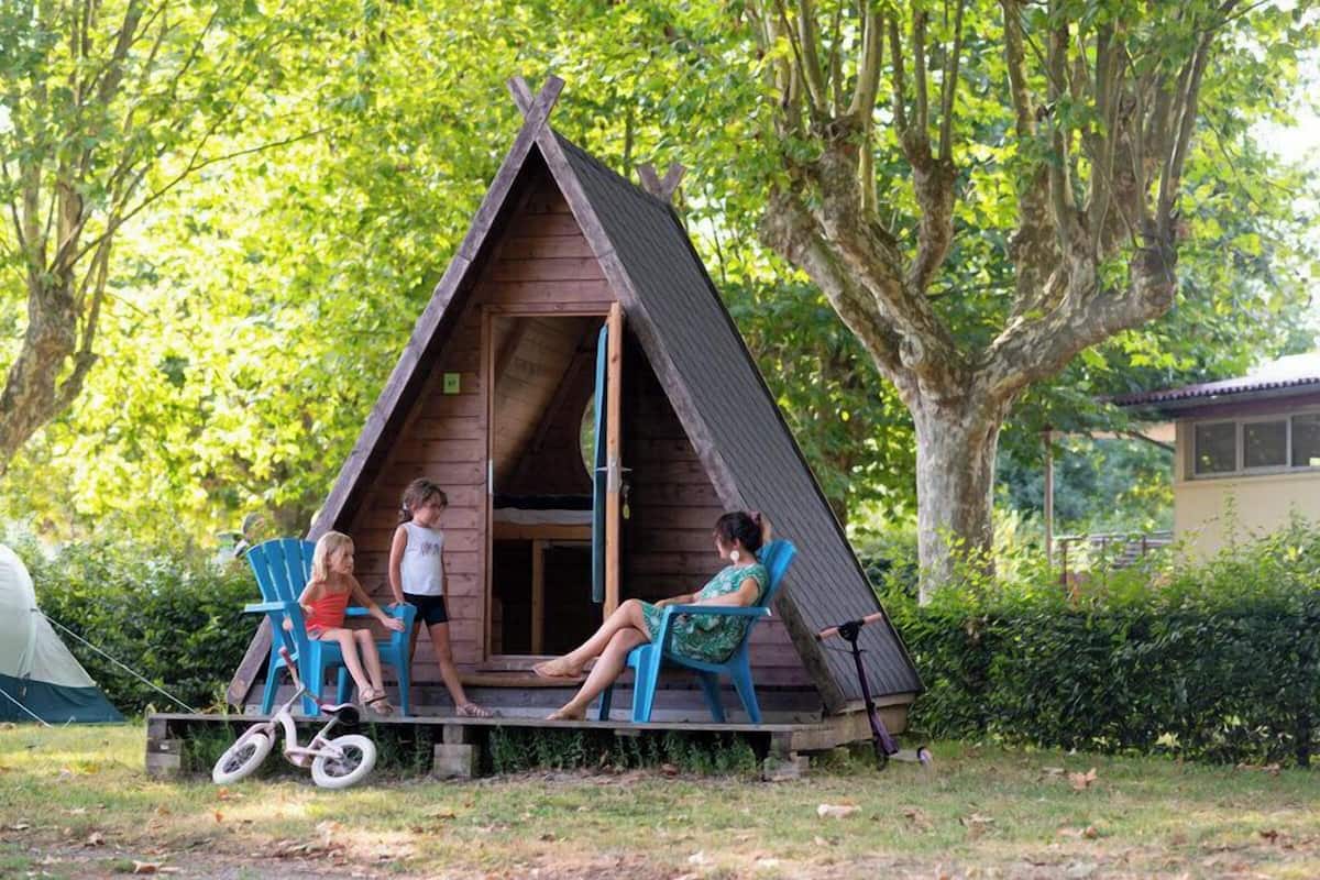 Une structure en bois en forme de toit à deux versants, avec un porche, une tente et un vélo.