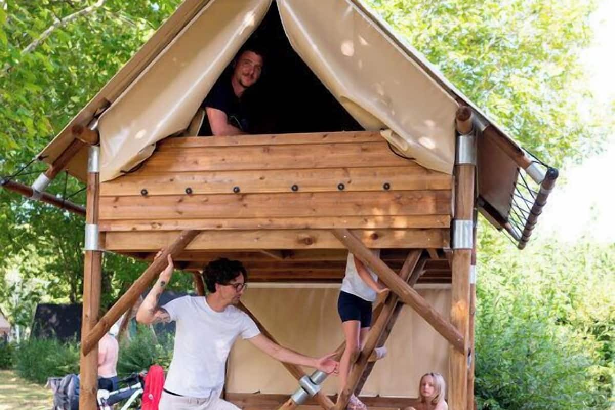 Une cabane en bois avec un toit incliné et une échelle permettant d’y accéder.