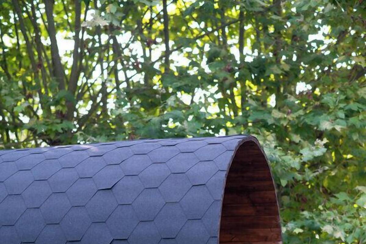 Une structure en bois, de type wagon, dotée d’un toit hexagonal et de roues en métal.