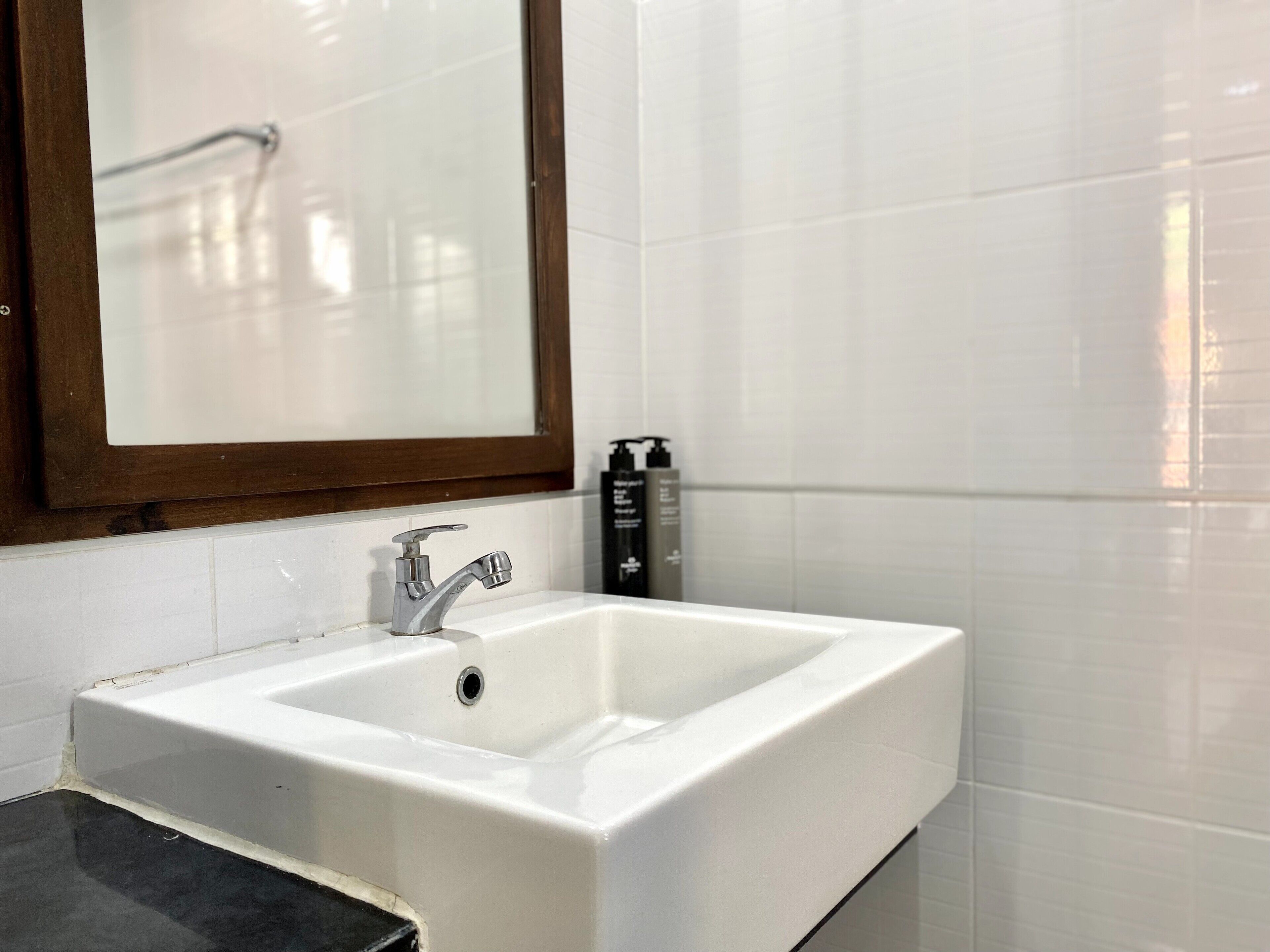 A bathroom with a white sink, a mirror, and two toiletries.