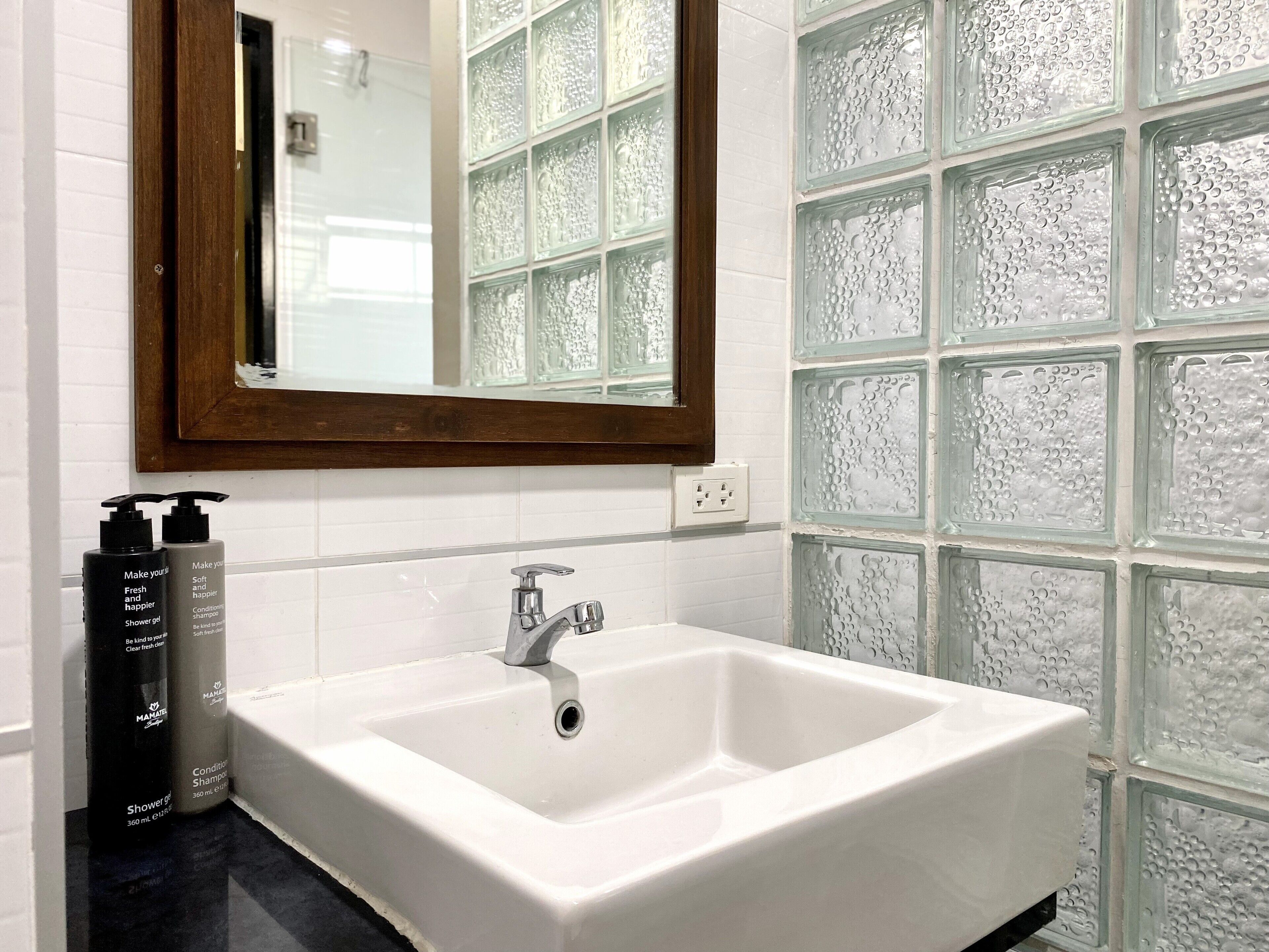 Een badkamer met een witte wastafel, een spiegel en twee flessen shampoo.
