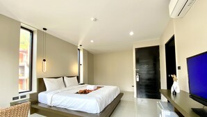 Ein modernes Hotelzimmer mit Bett, Schreibtisch, Fernseher und Blick ins Freie.