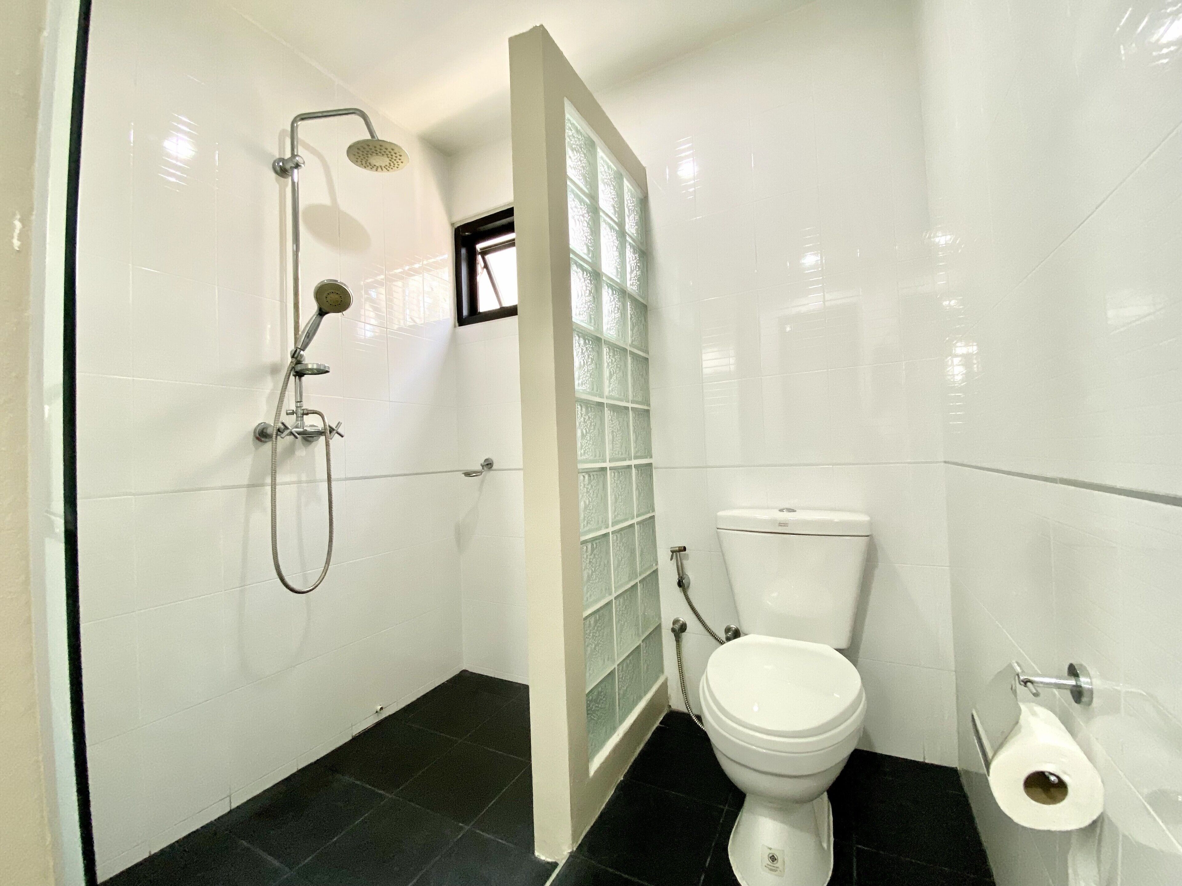 Une salle de bain avec douche, toilettes et une paroi de séparation en verre.