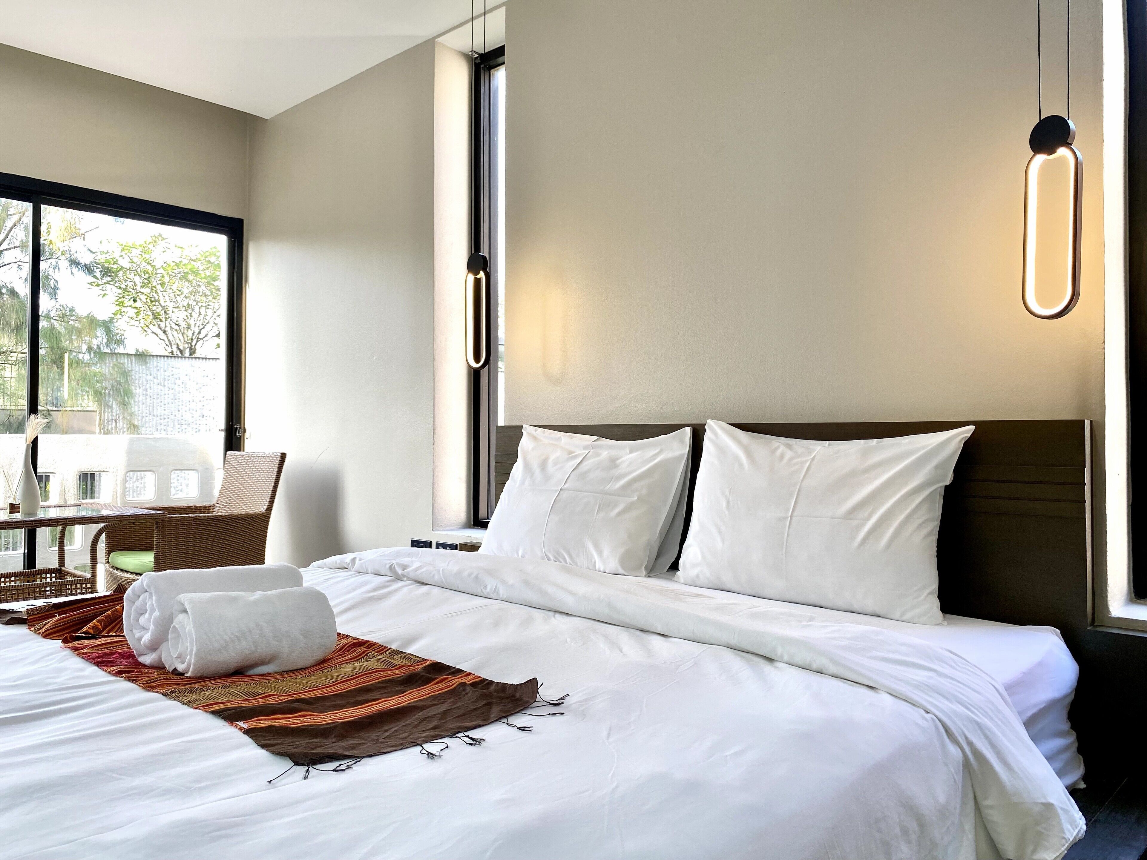 A hotel room with a bed, a chair, a table, and a window.