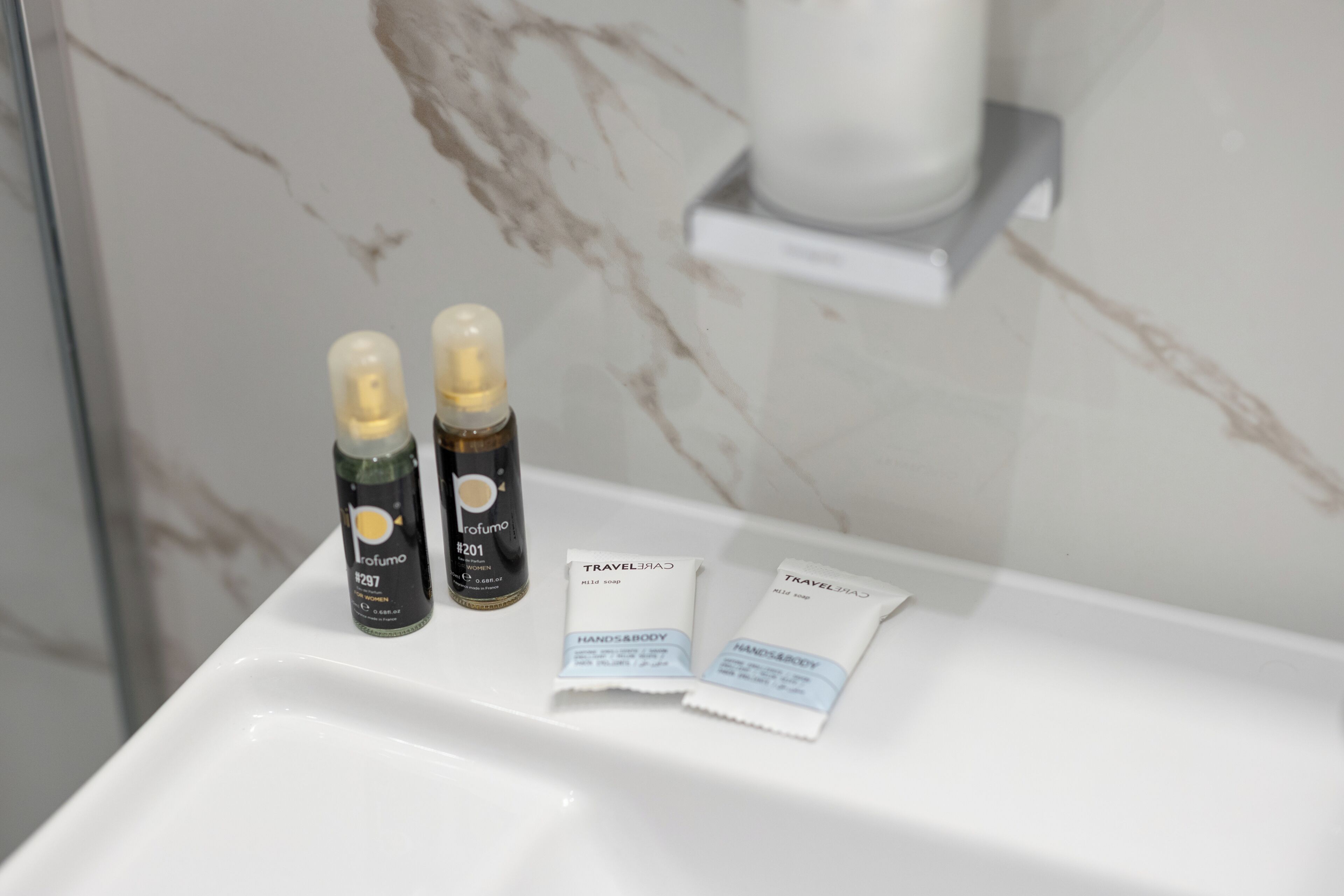 A bathroom sink with two toiletry bottles and two small packets of soap.