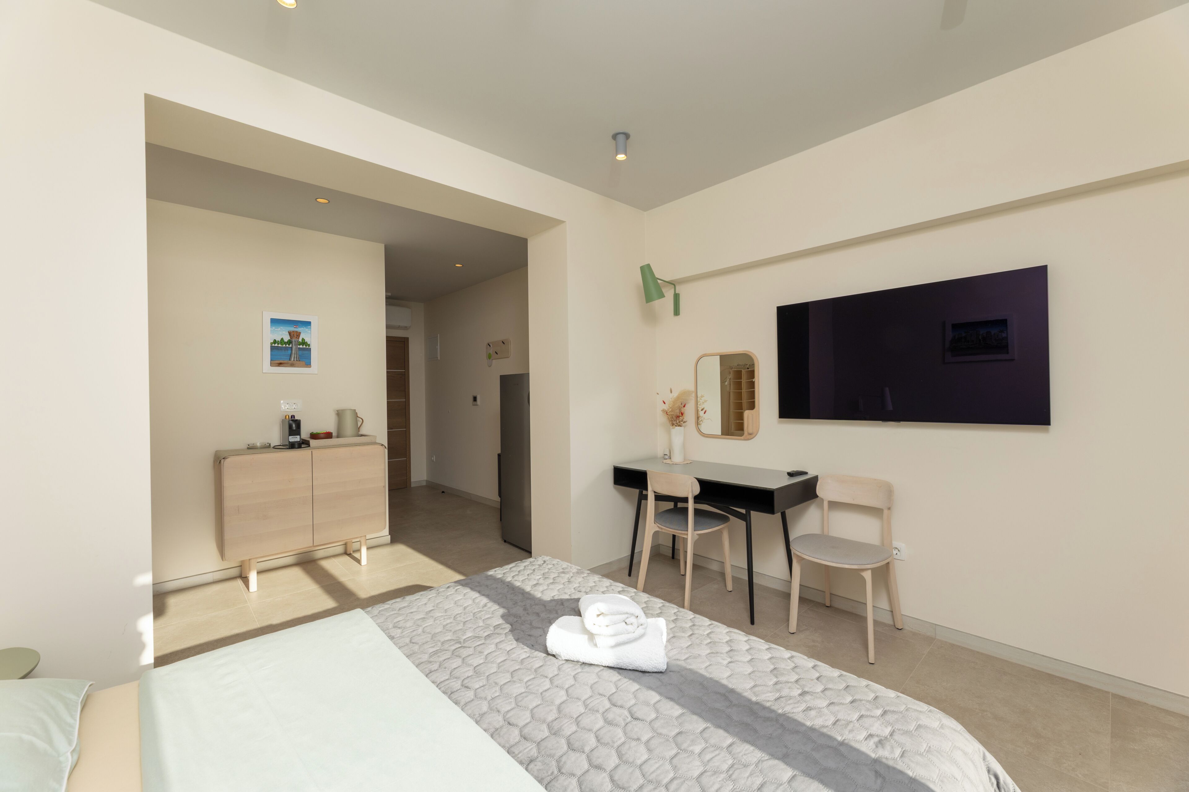 Una camera d'albergo con un letto, una scrivania, una sedia, una cassettiera, uno specchio e una televisione.