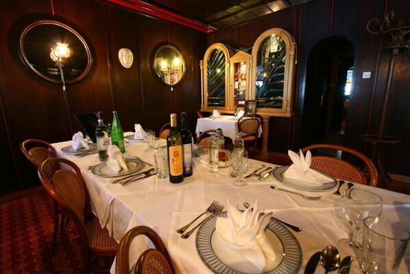A dining room with a long table set for a meal, featuring a wine bottle, glasses, and neatly arranged cutlery. - Villa Segetski dvori – Tradition since 1964 (Seget)