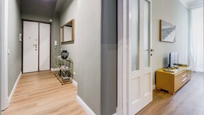Un couloir doté d’un plancher en bois, d’une vitrine contenant des livres, d’un miroir et d’un bureau avec un ordinateur et des documents.