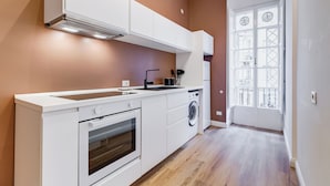 Une cuisine moderne avec des meubles blancs, un four encastré et un lave-linge.