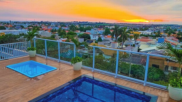 Una piscina en la azotea con vistas a un paisaje urbano al atardecer.