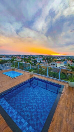 Une piscine sur le toit offrant une vue sur le paysage urbain au coucher du soleil.
