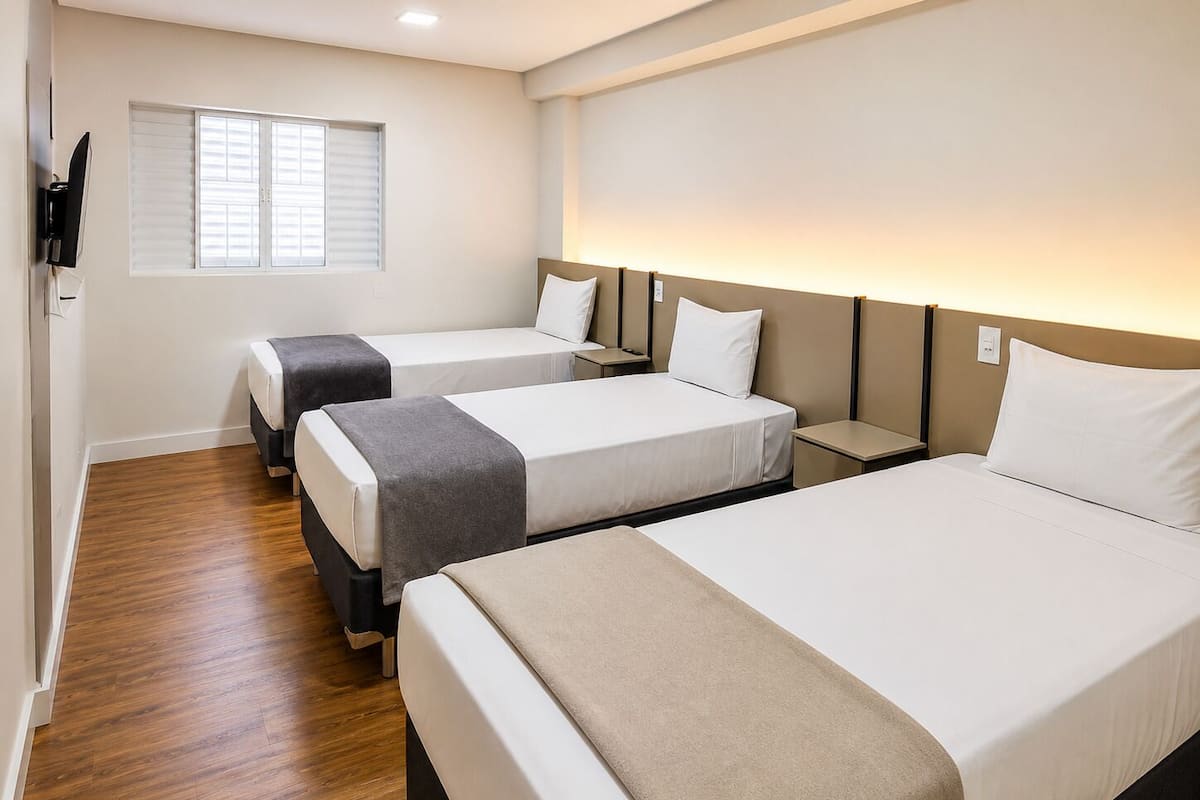 Une chambre dâhĂŽtel avec deux lits, un plancher en bois, une tĂ©lĂ©vision et une fenĂȘtre avec des stores.