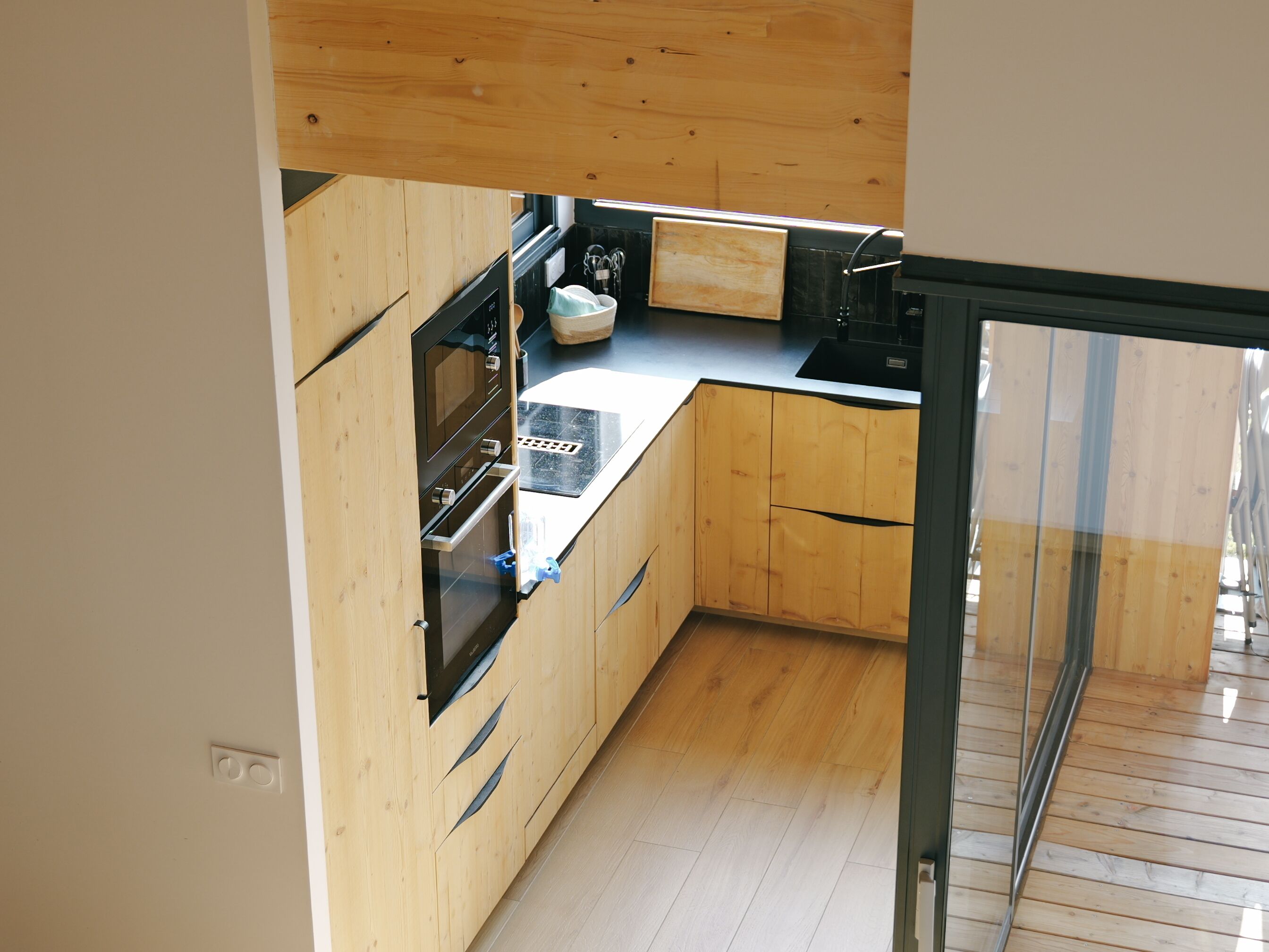 Una cucina moderna con mobili in legno, un piano di lavoro nero e un forno integrato.