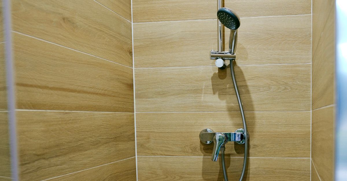 A shower area with wooden tiles and a handheld showerhead.