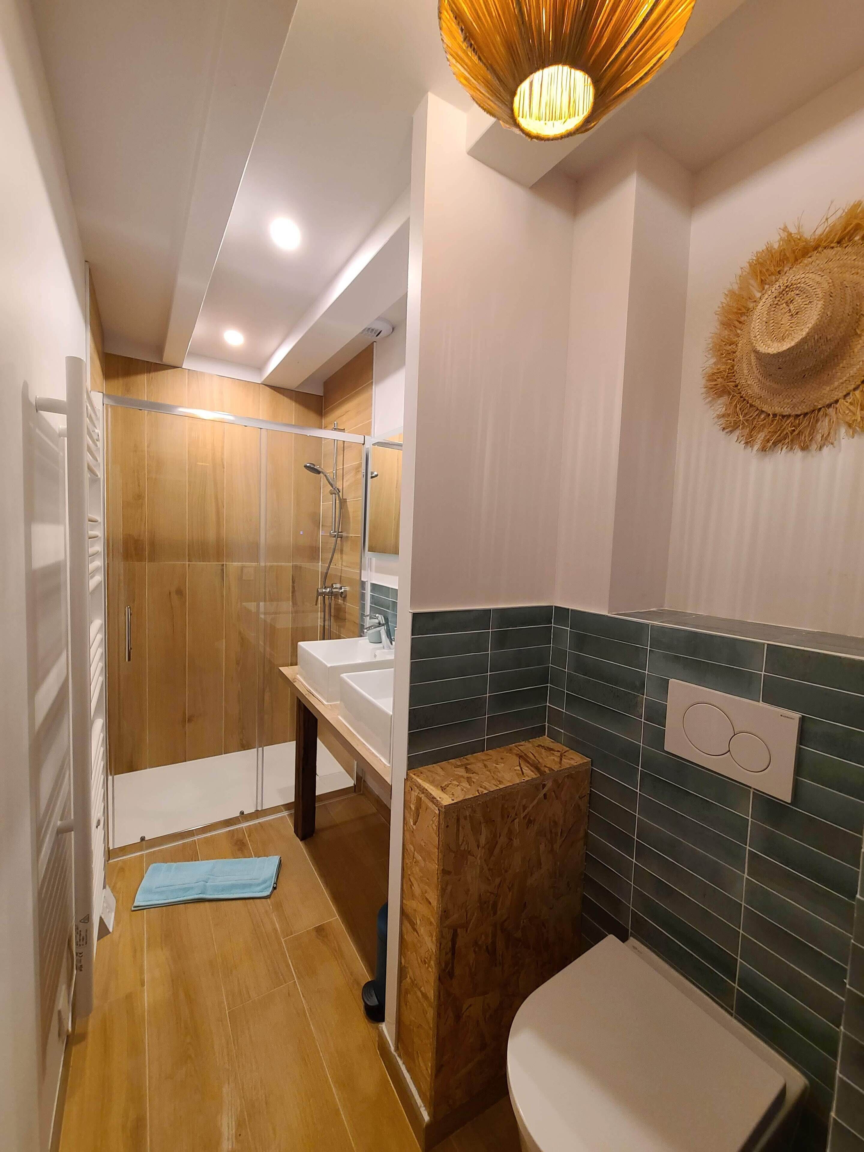 A modern bathroom with a glass-enclosed shower, a wooden vanity, and a toilet.