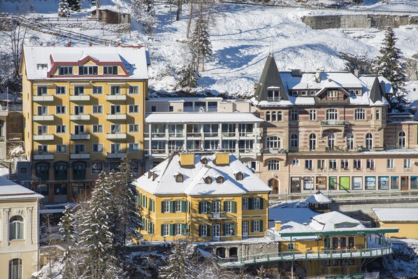 A multi-story hotel with a snow-covered roof, a balcony, and a view of a river. - Apartment Bad Gastein Near Ski Lift (Bad Gastein)