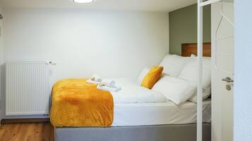 A hotel room with a bed, a radiator, and a door.