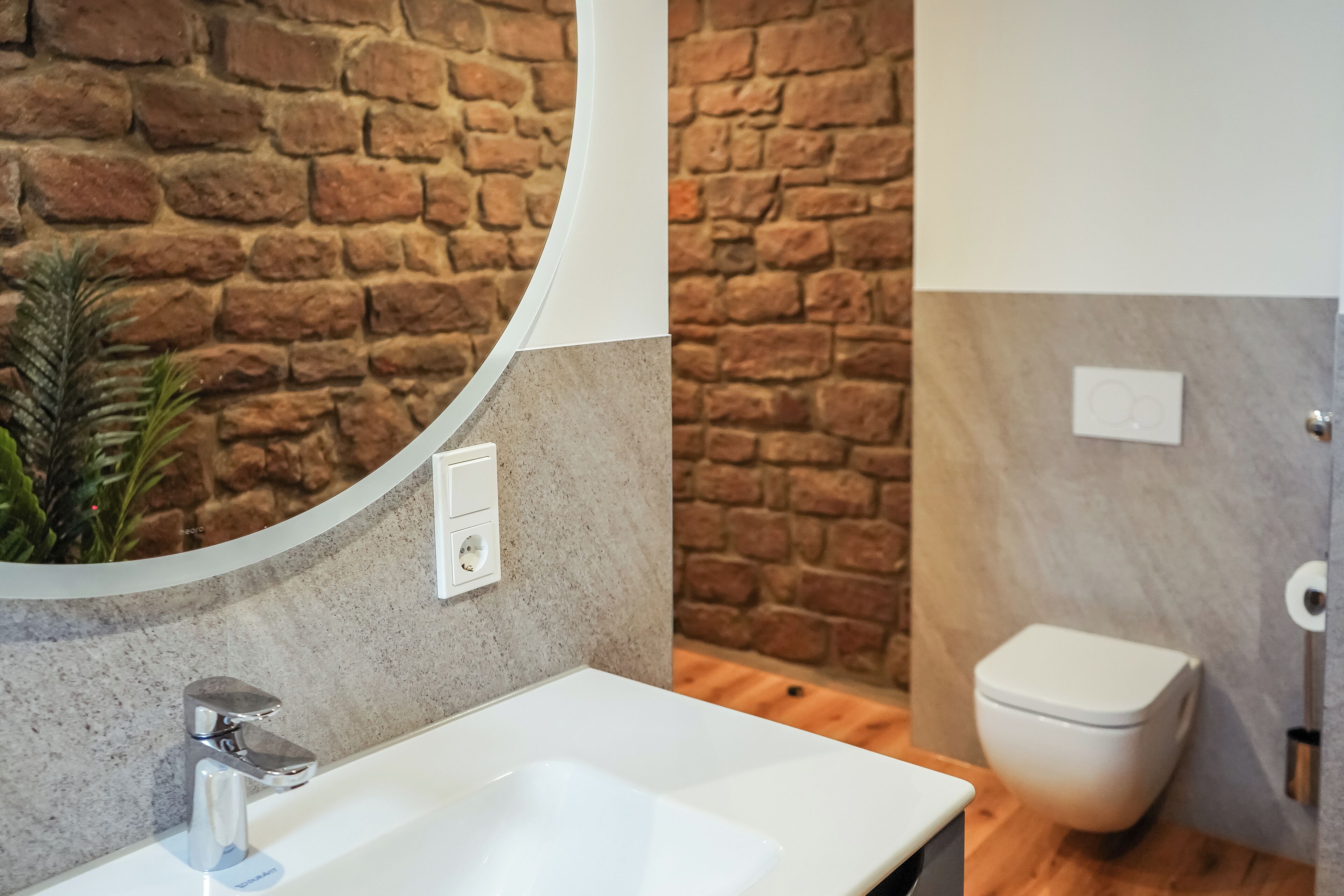 Ein Badezimmer mit Steinwand, Waschbecken in Weiß und Toilette.