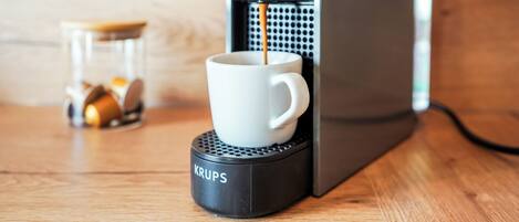 A coffee machine with a cup of coffee on a Krups coffee pod warmer.