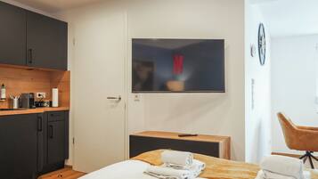 Ein Hotelzimmer mit Bett, Wandfernseher, Schreibtisch aus Holz, Stuhl und Kleiderschrank.