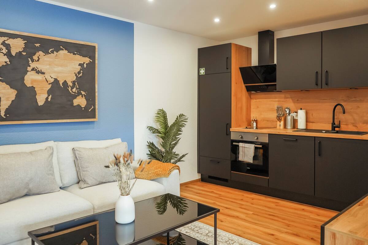 A modern living room with a white sofa, a black coffee table, and a world map on the wall.