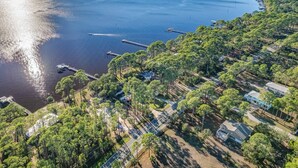 Vista aérea de una zona costera con un puerto deportivo, abundante vegetación y edificios residenciales.