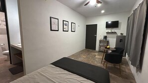Cozy retreat with a neatly made bed, desk, and flat-screen TV.