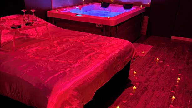 Ein Zimmer mit einem Bett, einer Massageliege und Holzdielen mit Kerzen.