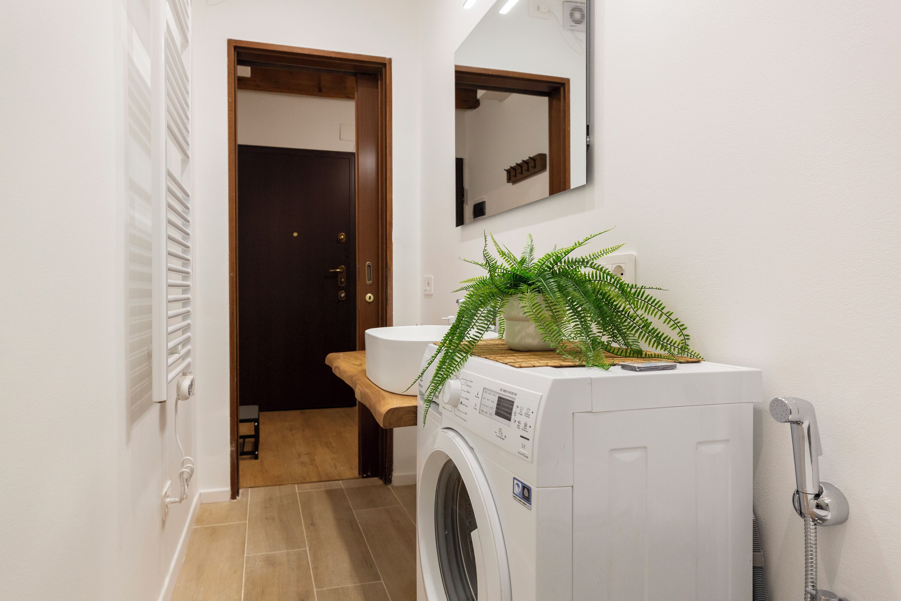 Un baño pequeño con lavadora, lavamanos y espejo.
