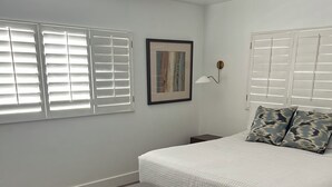 A bedroom with a bed, bench, ceiling fan, and windows with blinds. - Charming 3-bedroom house with AC and WiFi in Palm Springs (Palm Springs)