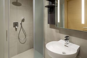 Sink and shower area with a large mirror above.