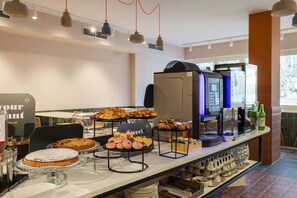 A buffet area with various pastries and baked goods displayed on stands. - B&B HOTEL Como Baradello (Como)