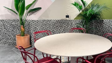 Une table ronde entourée de six chaises rouges, le tout agrémenté de carreaux décoratifs et de plantes en pot.
